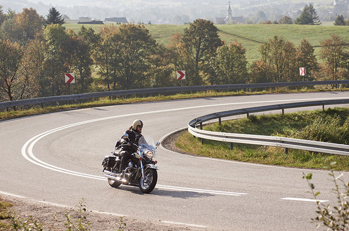 Person riding motorcycle around sharp corner in country setting